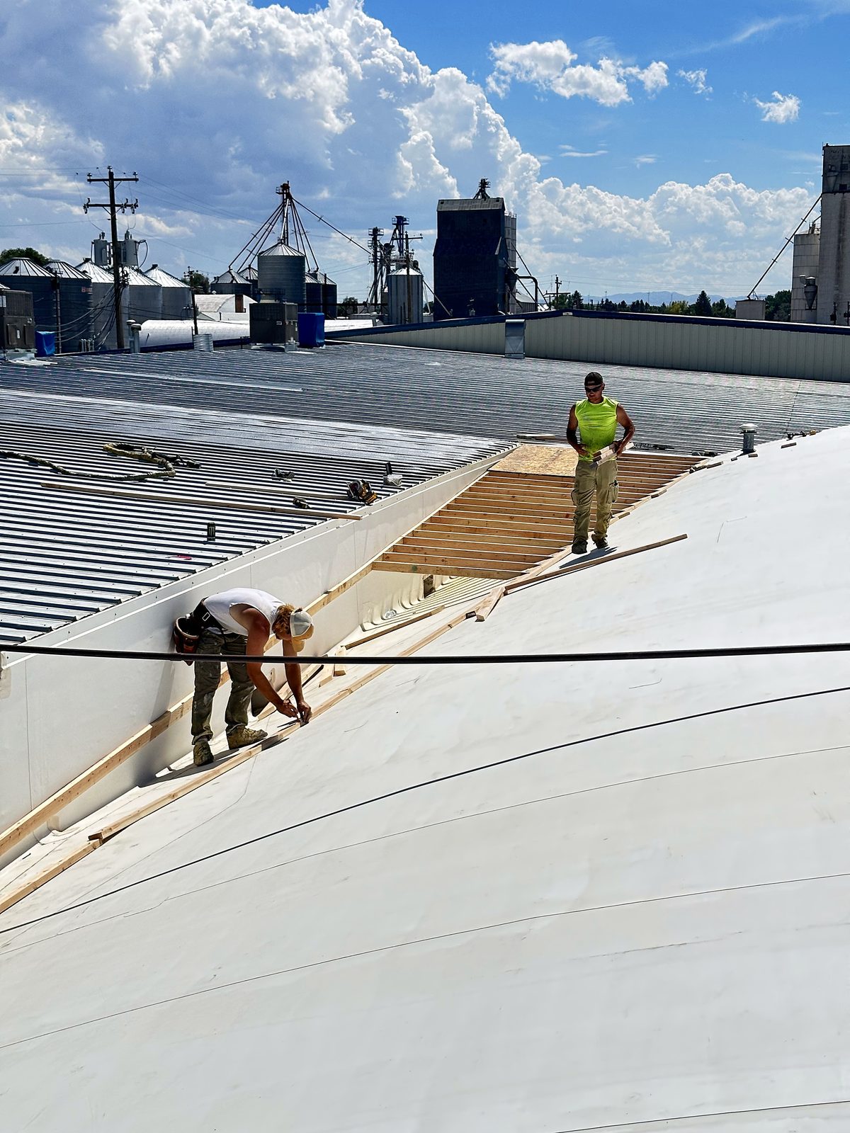Crew working on a metal roof coating job near grain elevators at Driscoll Potatoes, American Falls, Idaho