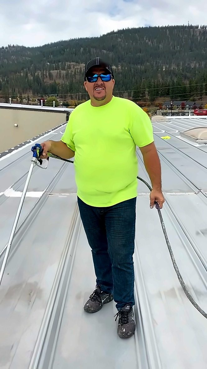 Crew member holding a spray gun on a metal roof