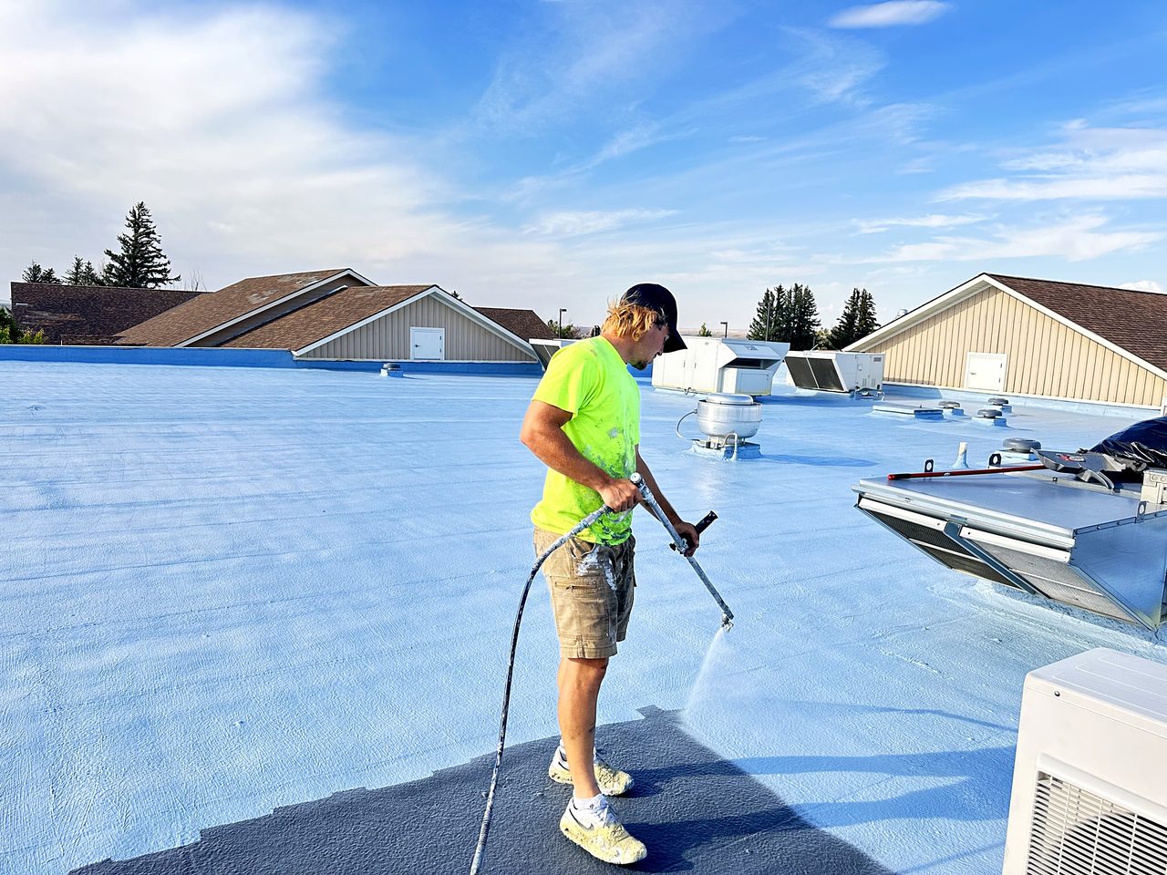 Revive crew member spraying roof coating on a City of Cut Bank, Montana building