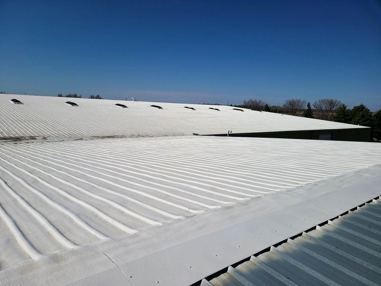 The white spray foam roof at Duratech Industries in Jamestown, ND, under a clear sky (2021 inspection)